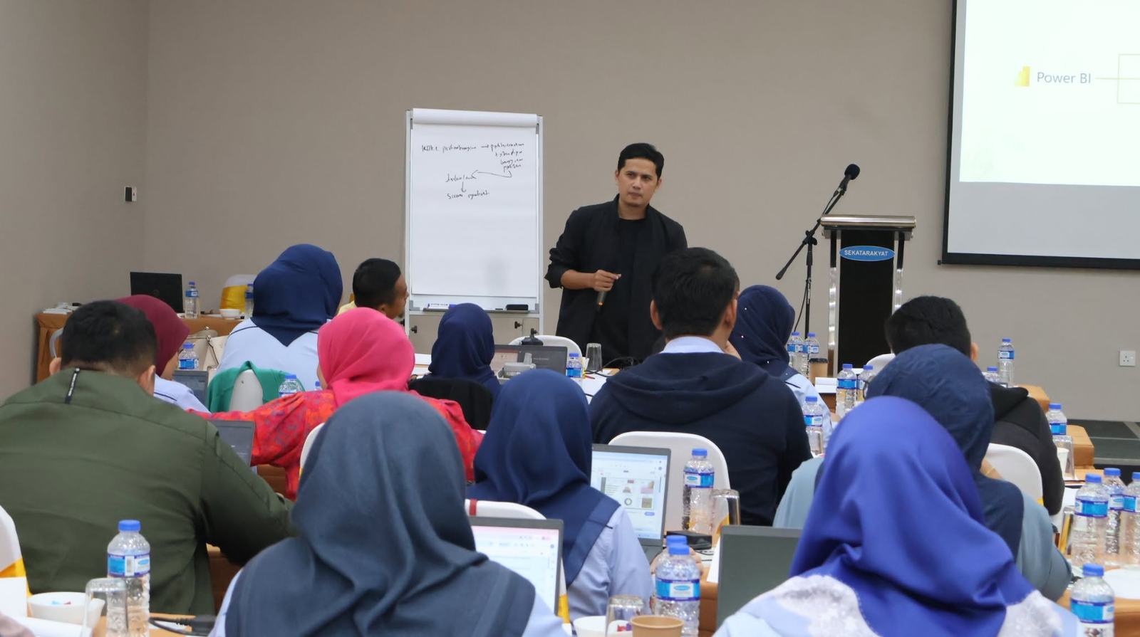 Jurulatih menerangkan topik Power BI kepada peserta